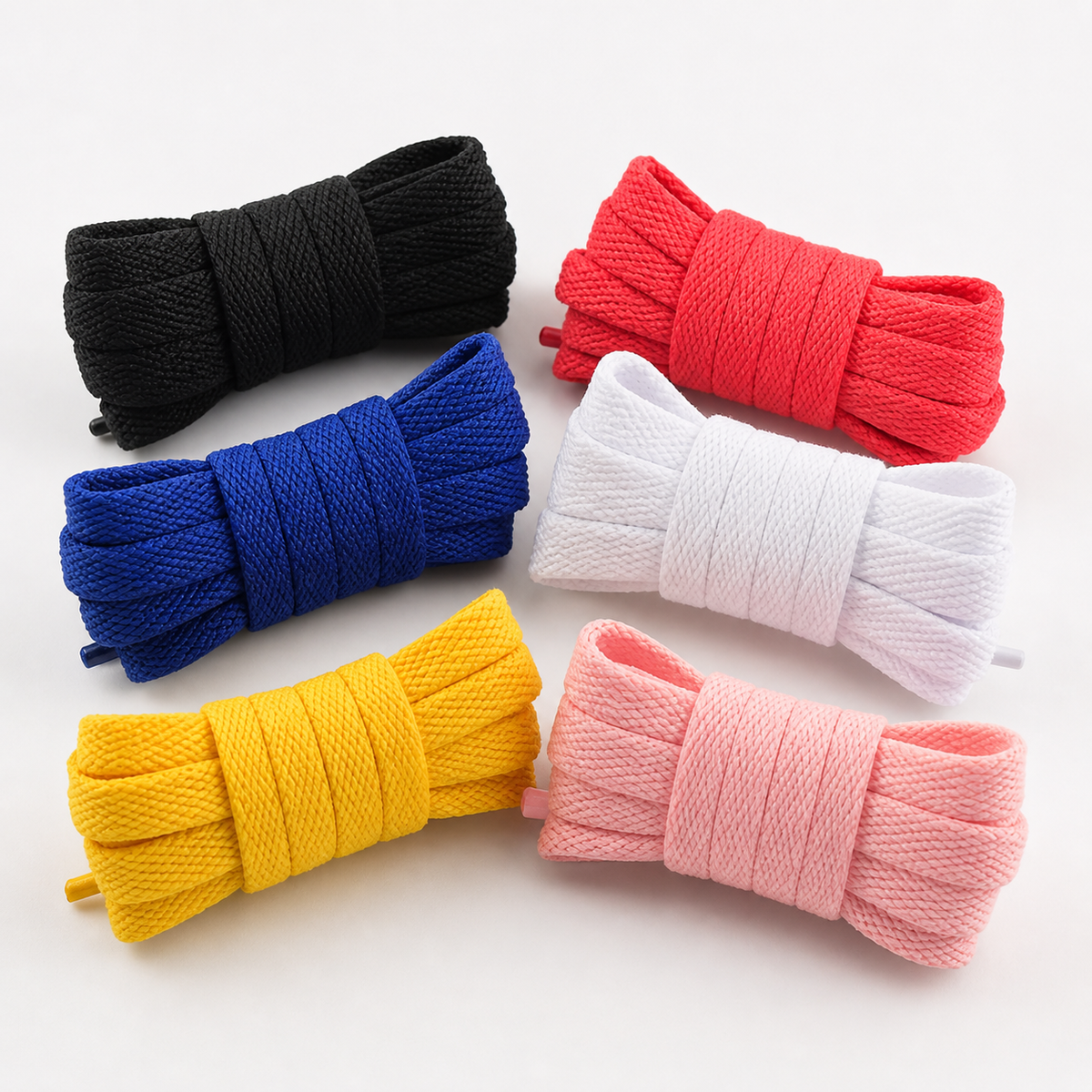 Set of colorful shoelaces in black, red, blue, white, yellow, and pink on a light background.